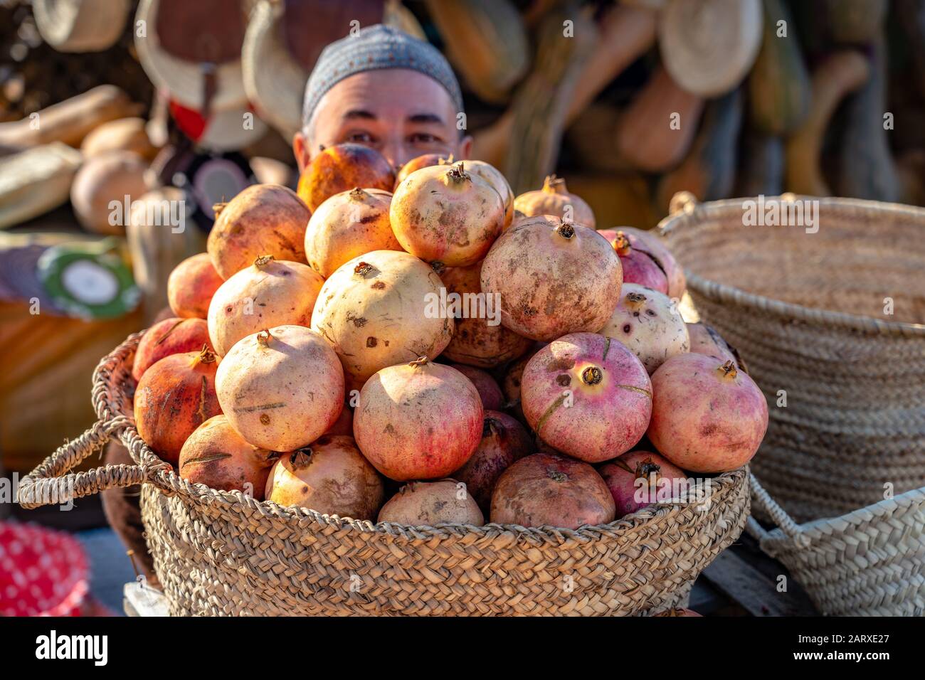 Meknes, Morocco - Friendly salesman hiding behind pomegranates Stock Photo