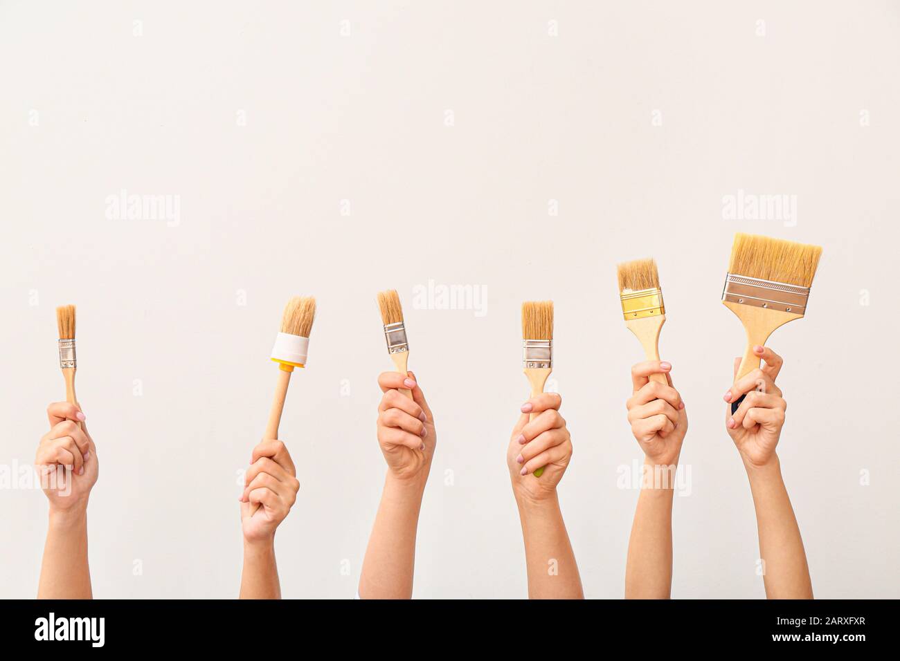 Female hands with paint brushes on white background Stock Photo - Alamy