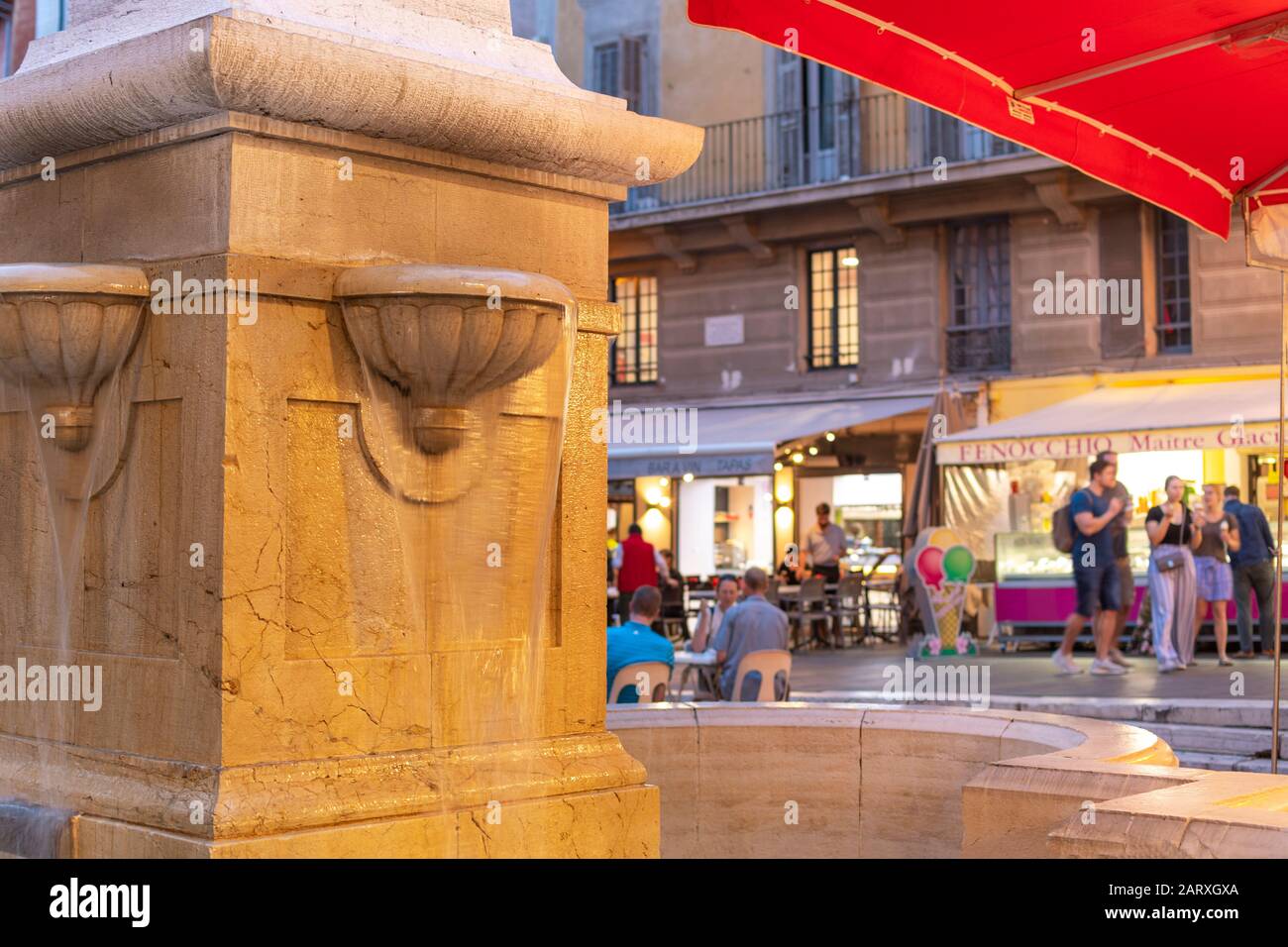 Water cascades from the historic obelisk fountain in Place Rossetti in the Old Town Vieux Nice center full of shops, cafes and churches in Nice France Stock Photo