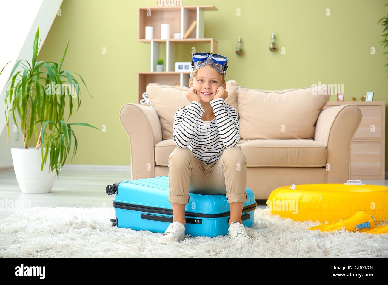 Cute little boy sitting on suitcase at home Stock Photo Alamy