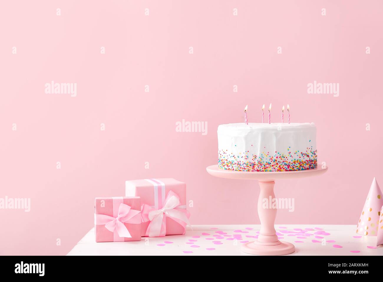 Tasty Birthday cake with gifts on table against color background Stock ...