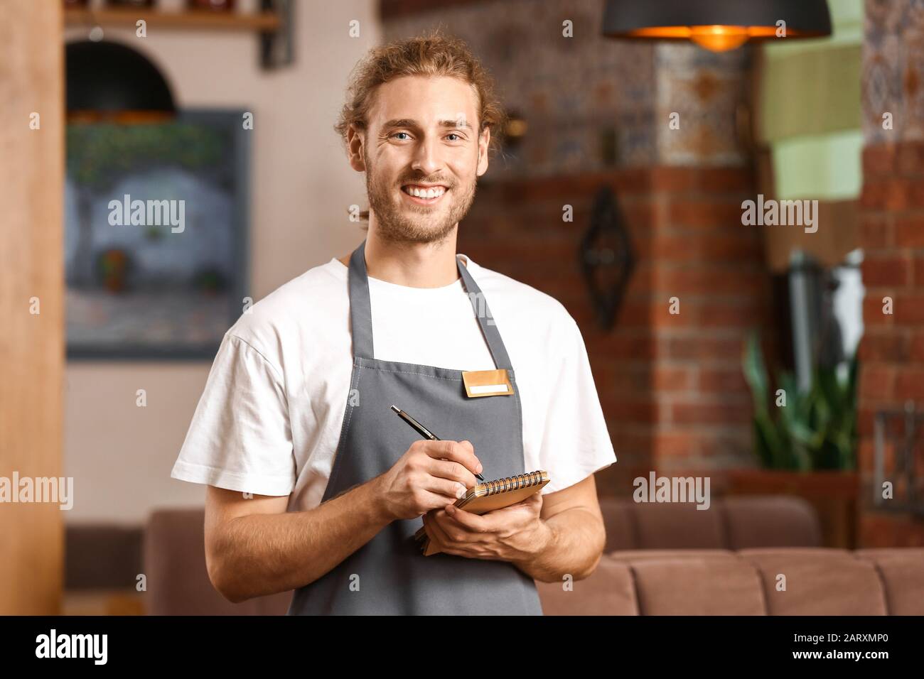Young male waiter in restaurant Stock Photo