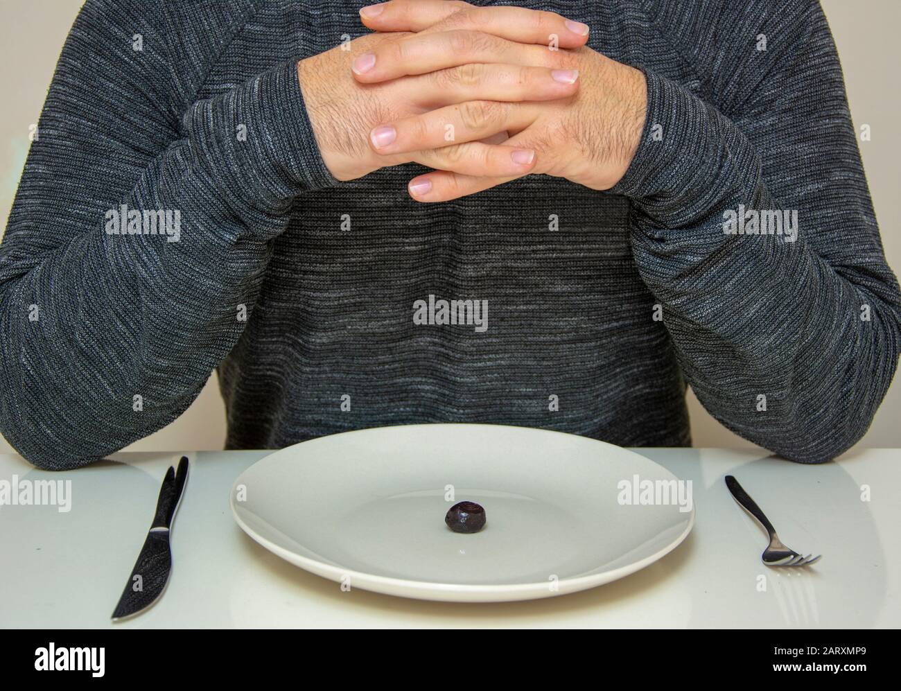 Man with hands tied looking at plate Stock Photo