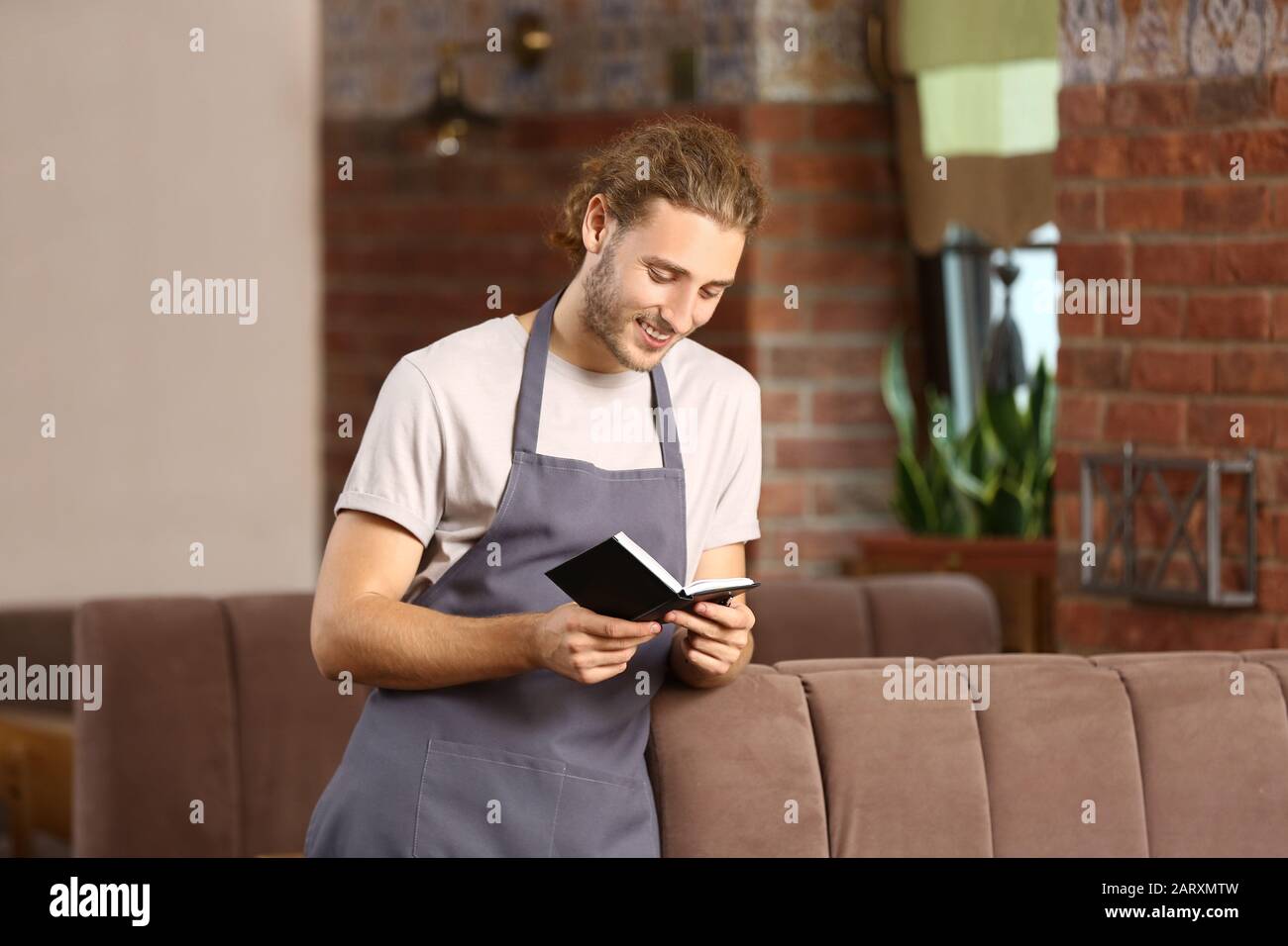 Young male waiter in restaurant Stock Photo