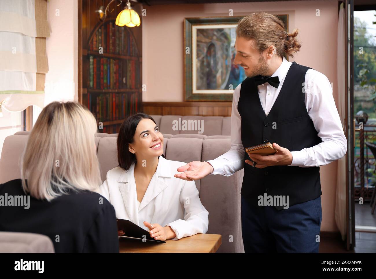 Waiter serving clients in restaurant Stock Photo Alamy