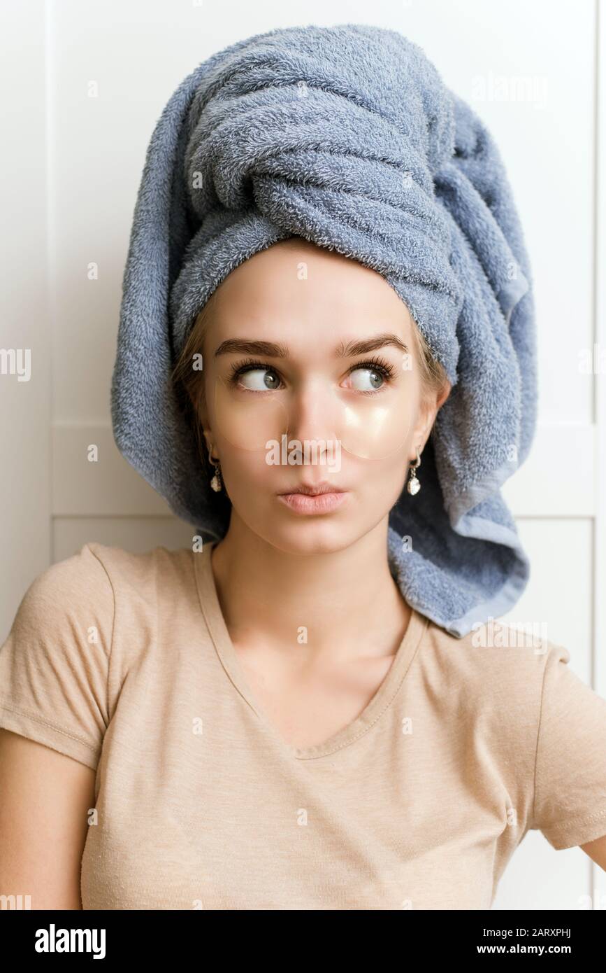 Patch for the area under the eyes. Facial skin care. A young girl watches her skin. Surprised and funny face of a girl during a morning routine. Stock Photo