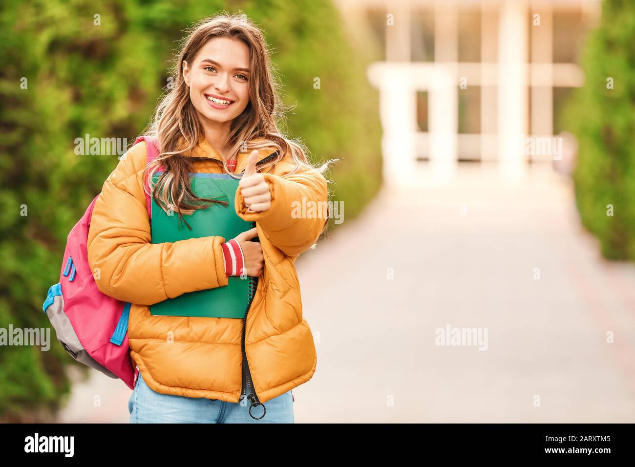 Portrait of teenage female student showing thumb-up outdoors Stock ...