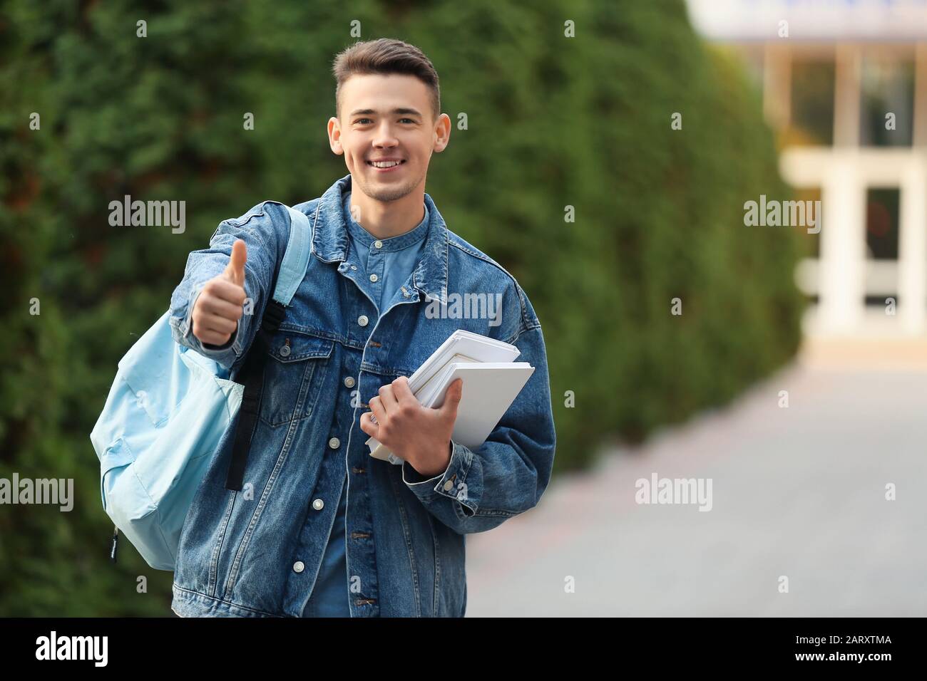 Portrait of teenage male student showing thumb-up outdoors Stock Photo ...