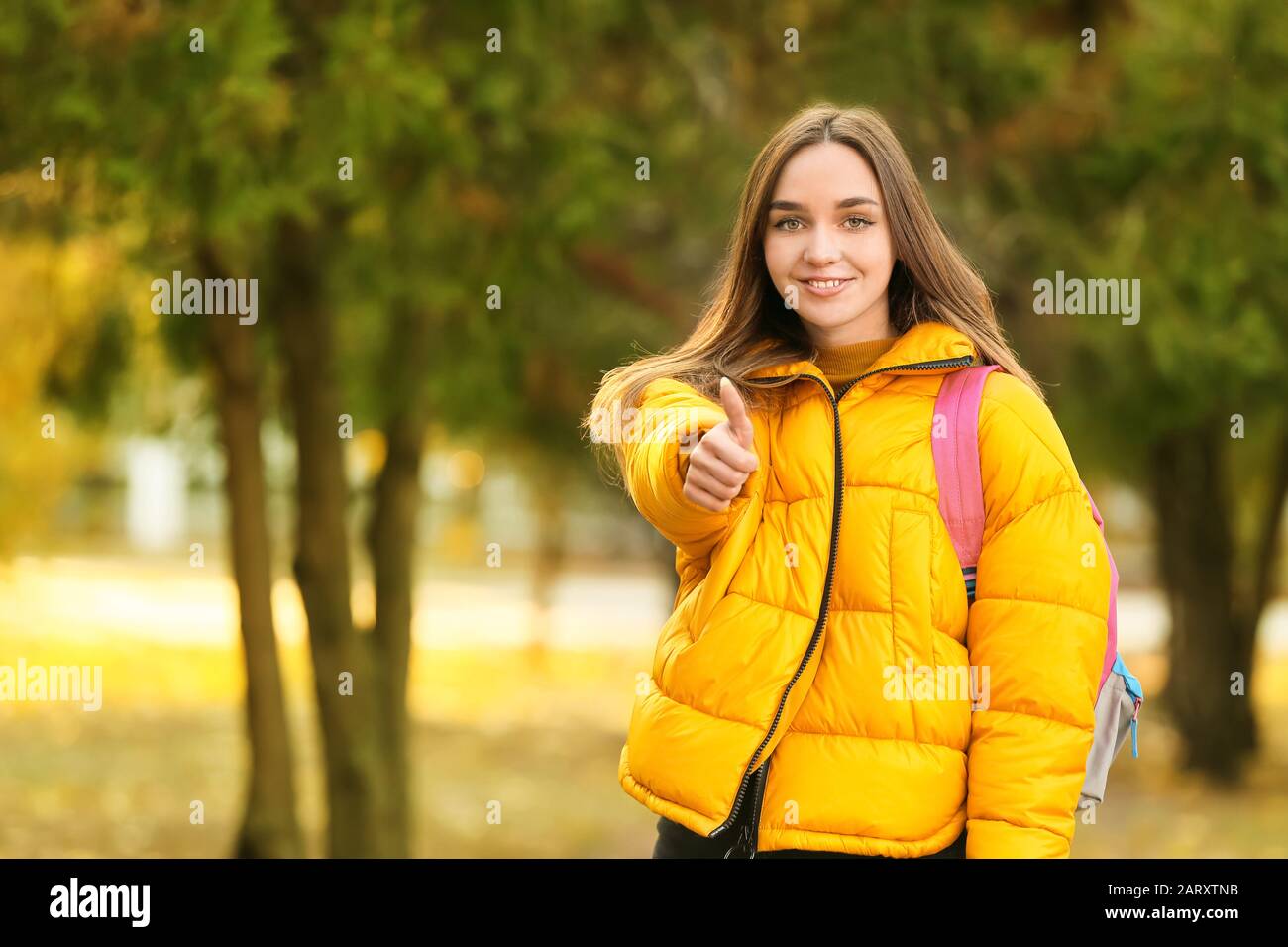 Portrait of teenage female student showing thumb-up outdoors Stock ...