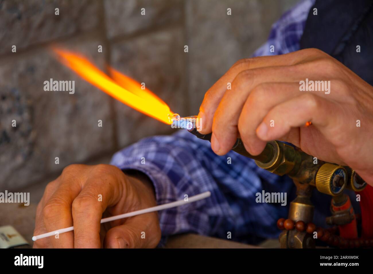 Glass artist shapes the material in his hand with fire. Place of Work, Studio - Workplace, Glass, Wind Stock Photo