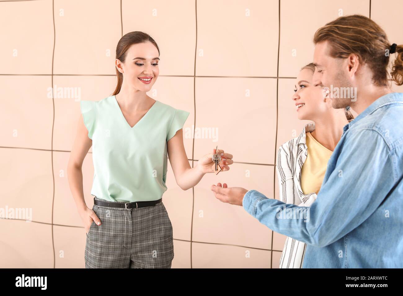 Real estate agent giving a key from new house to young couple Stock ...