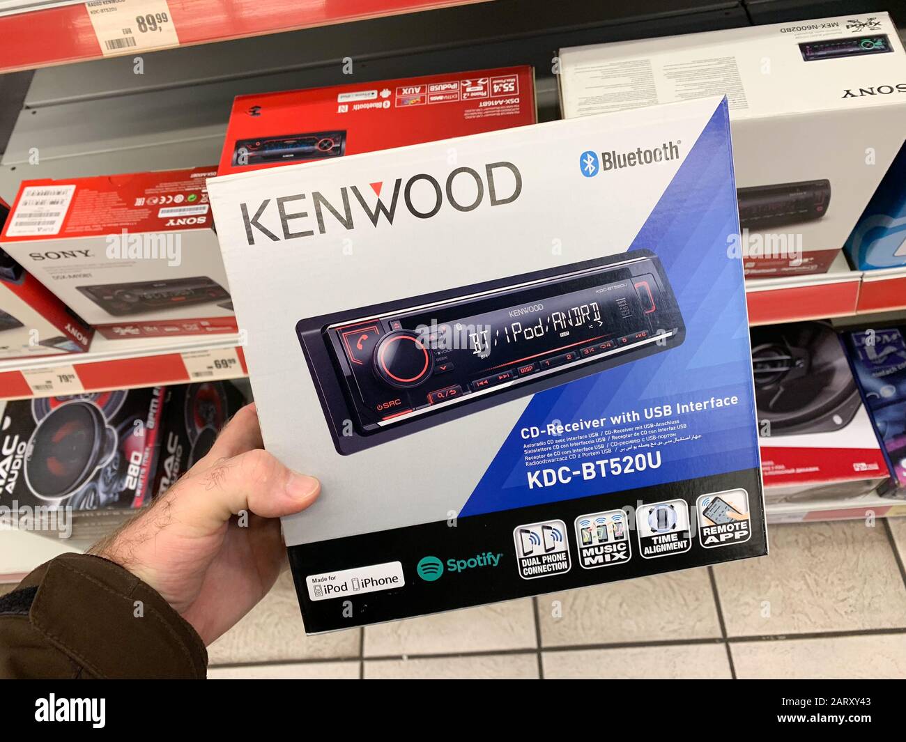 Dortmund, Germany - Mar 25, 2019: Man customer hand holding package of new  auto radio manufactured by Kenwood modern KDC-BT-520U with amplifier, ipod  usb connection and DAB digital radio and Remote app