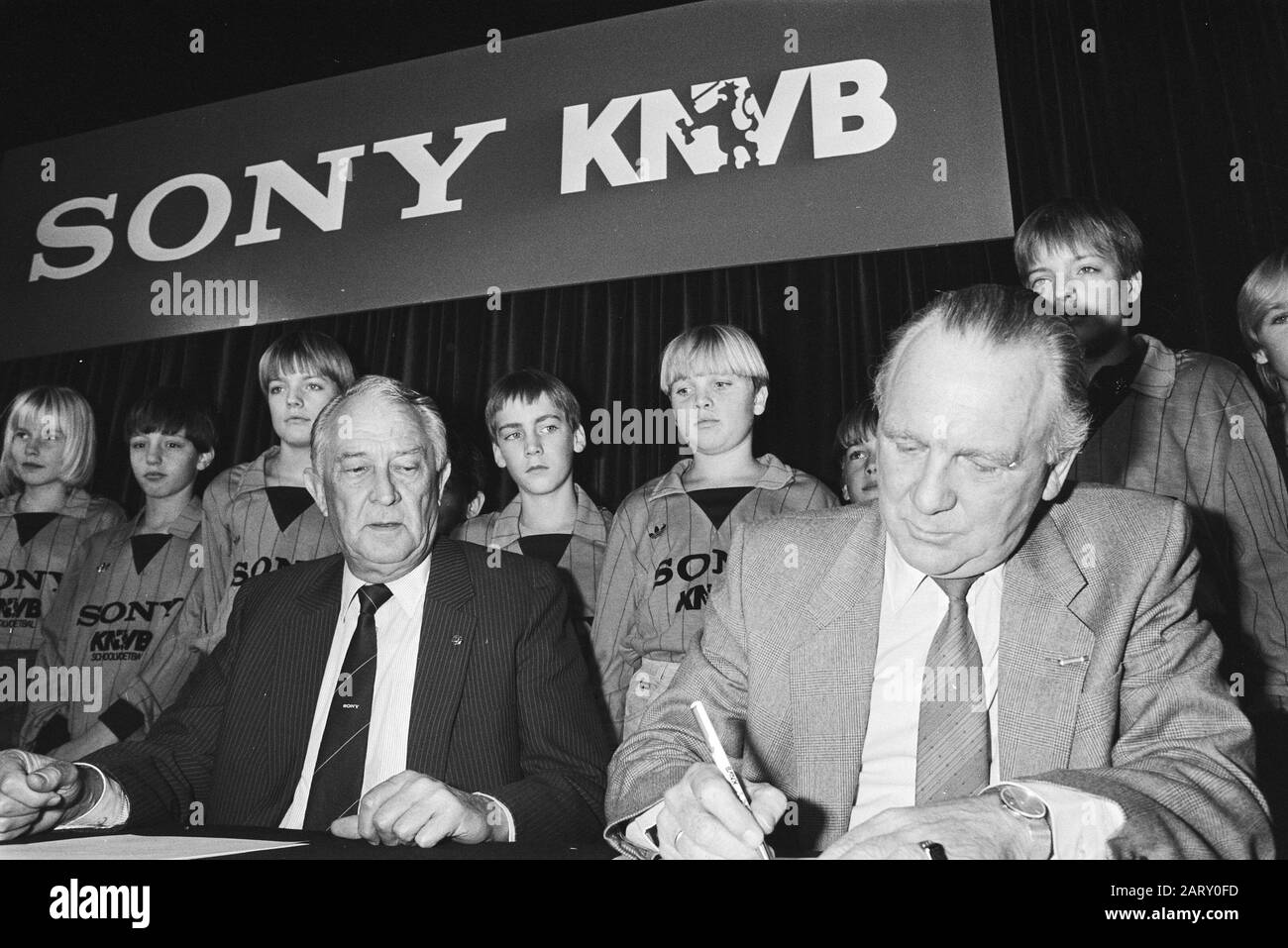 Sponsorcontract signed Sony-KNVB  Chairman of the KNVB Van Marle (r) and Mr. A. (Ton) Brandsteder of Sony signs in the presence of youth Date: November 14, 1983 Keywords: youth, enterprises, agreements, sponsorship, football, chairmen Personal name: Brandsteder, A, Marle, J.W. of Institution Name: Sony Stock Photo