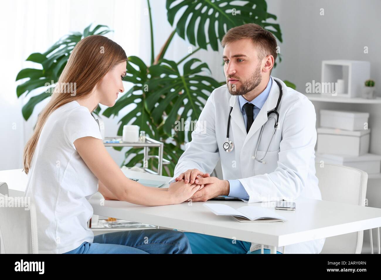 Male doctor calming sad female patient in clinic Stock Photo - Alamy