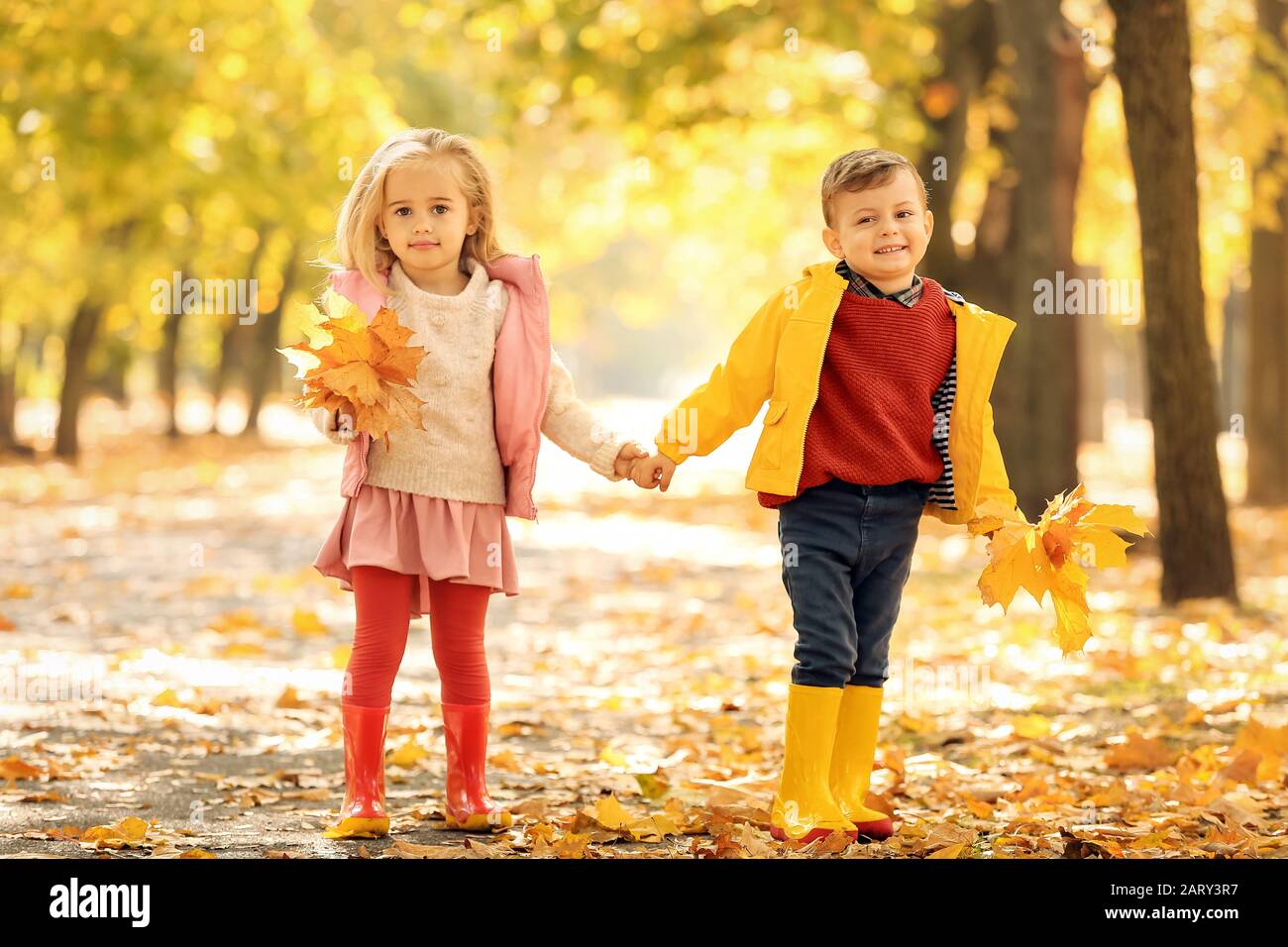 Cute little children with leaves in park on autumn day Stock Photo