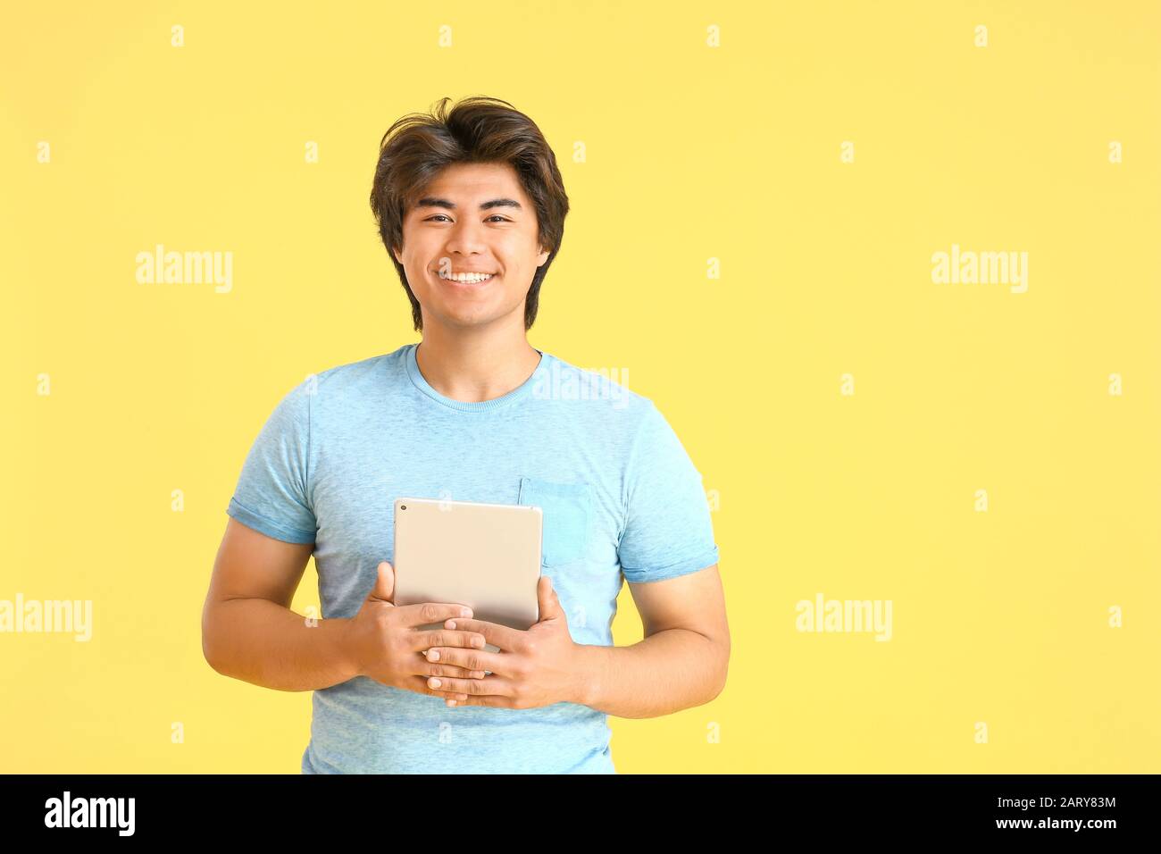 Male Asian programmer with tablet computer on color background Stock Photo