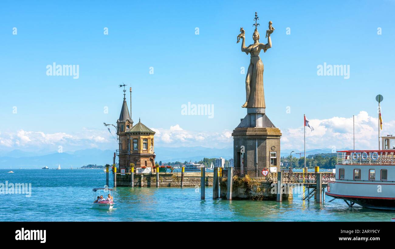 Constance, Germany – July 30, 2019: Old lighthouse and big statue of Imperia in harbor of Konstanz, Germany. Imperia is a landmark of the city. Panora Stock Photo