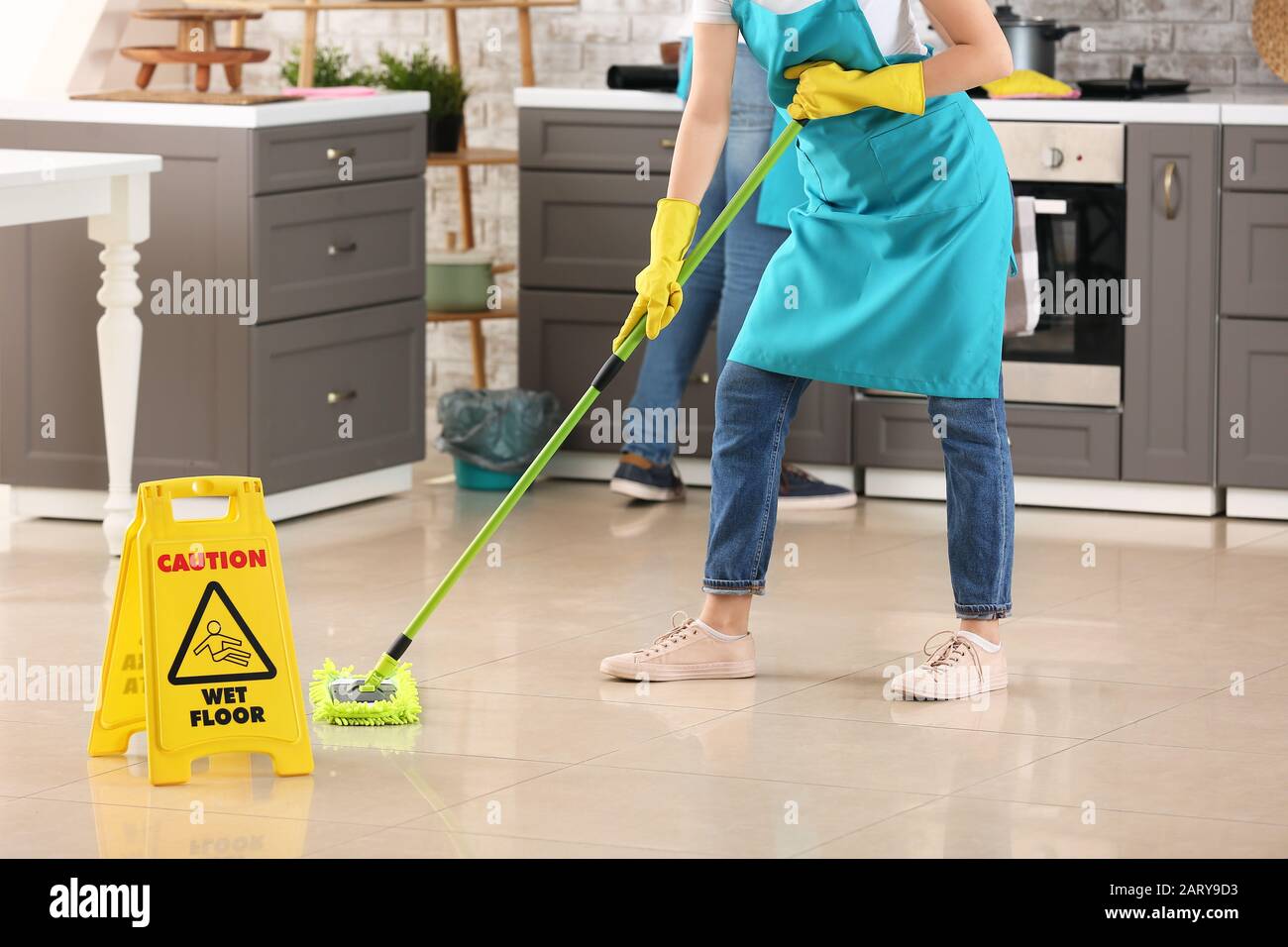Female janitor mopping floor in kitchen Stock Photo