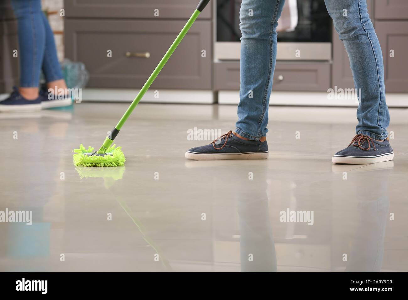 Male janitor mopping floor in kitchen Stock Photo