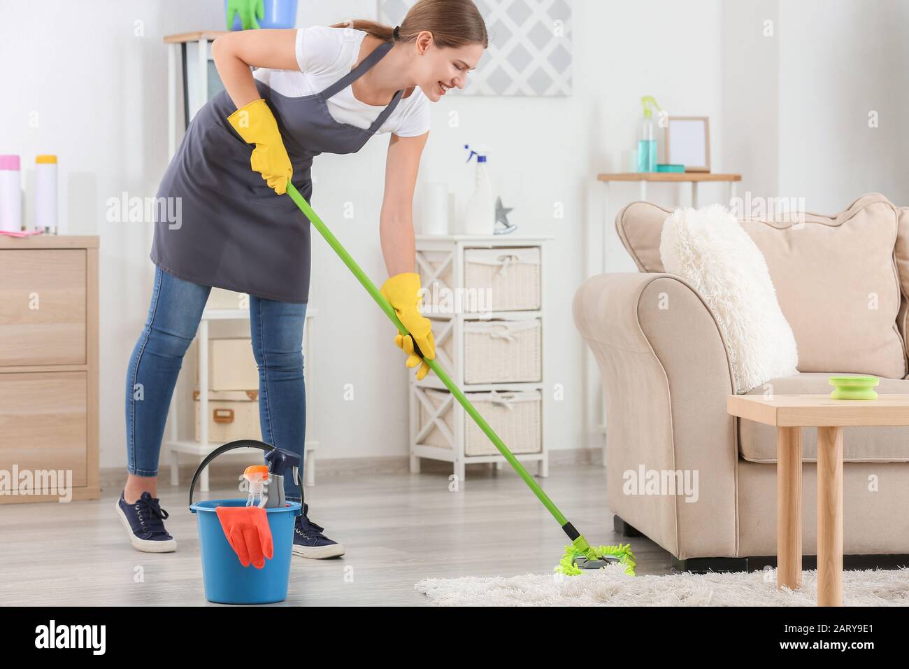 Female janitor mopping floor in room Stock Photo