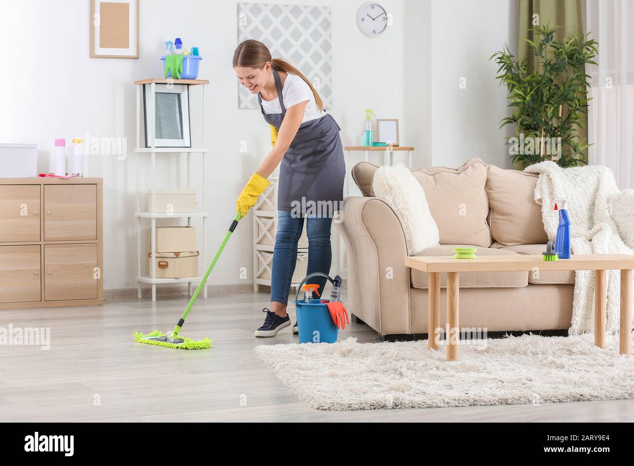 Female janitor mopping floor in room Stock Photo