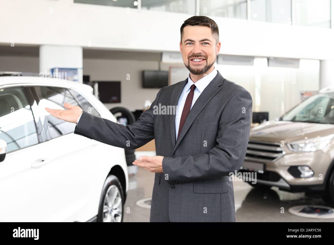 Salesman near car in modern salon Stock Photo Alamy