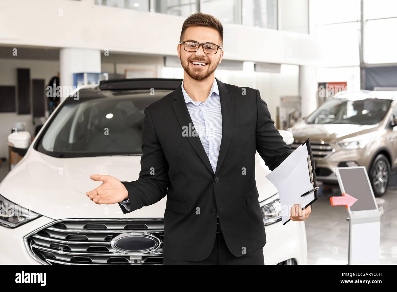 Salesman near car in modern salon Stock Photo Alamy