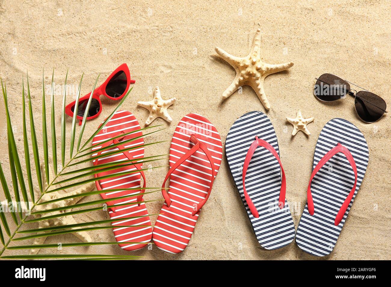 Stylish flip-flops with sunglasses and starfishes on sand Stock Photo ...