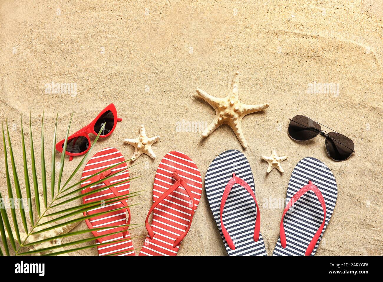 Stylish flip-flops with sunglasses and starfishes on sand Stock Photo ...