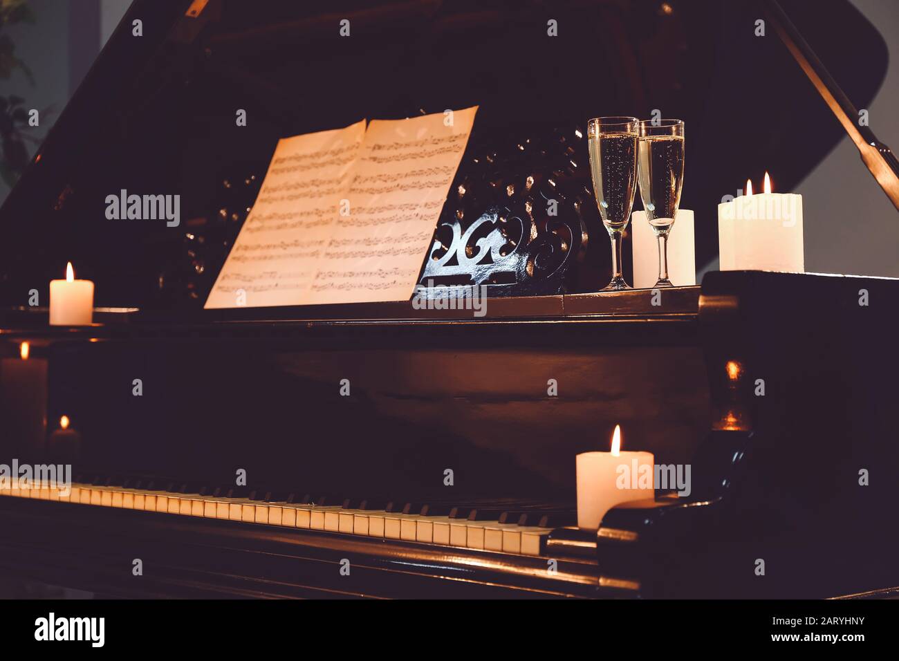 Stylish grand piano with burning candles and glasses of champagne in