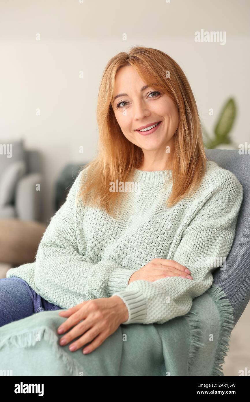 Beautiful mature woman sitting in armchair at home Stock Photo - Alamy