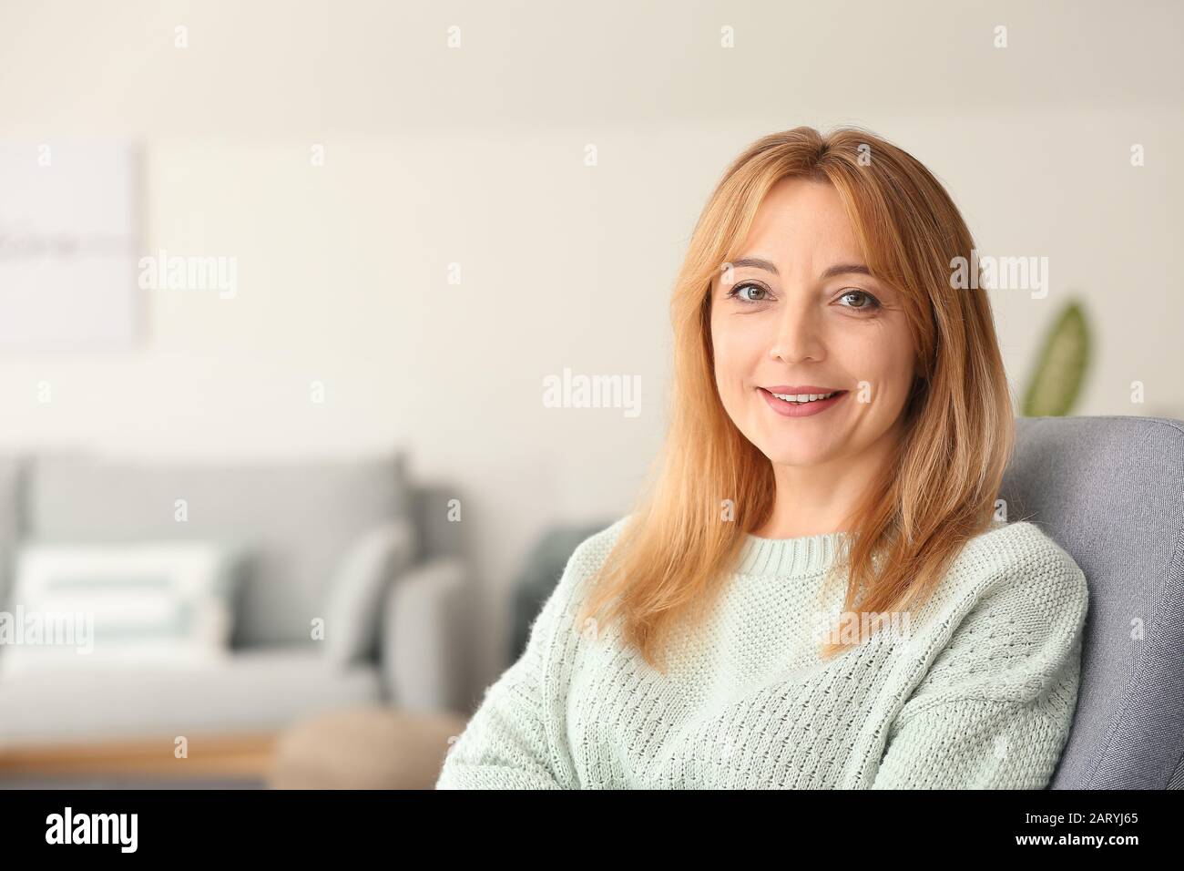 Beautiful mature woman sitting in armchair at home Stock Photo - Alamy