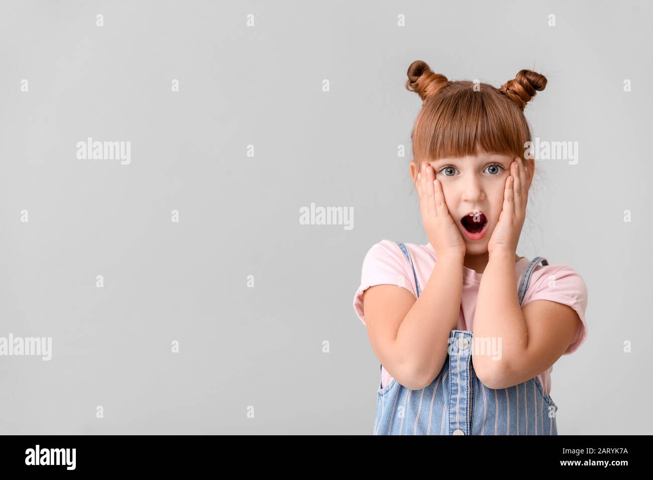 Surprised little girl on light background Stock Photo - Alamy