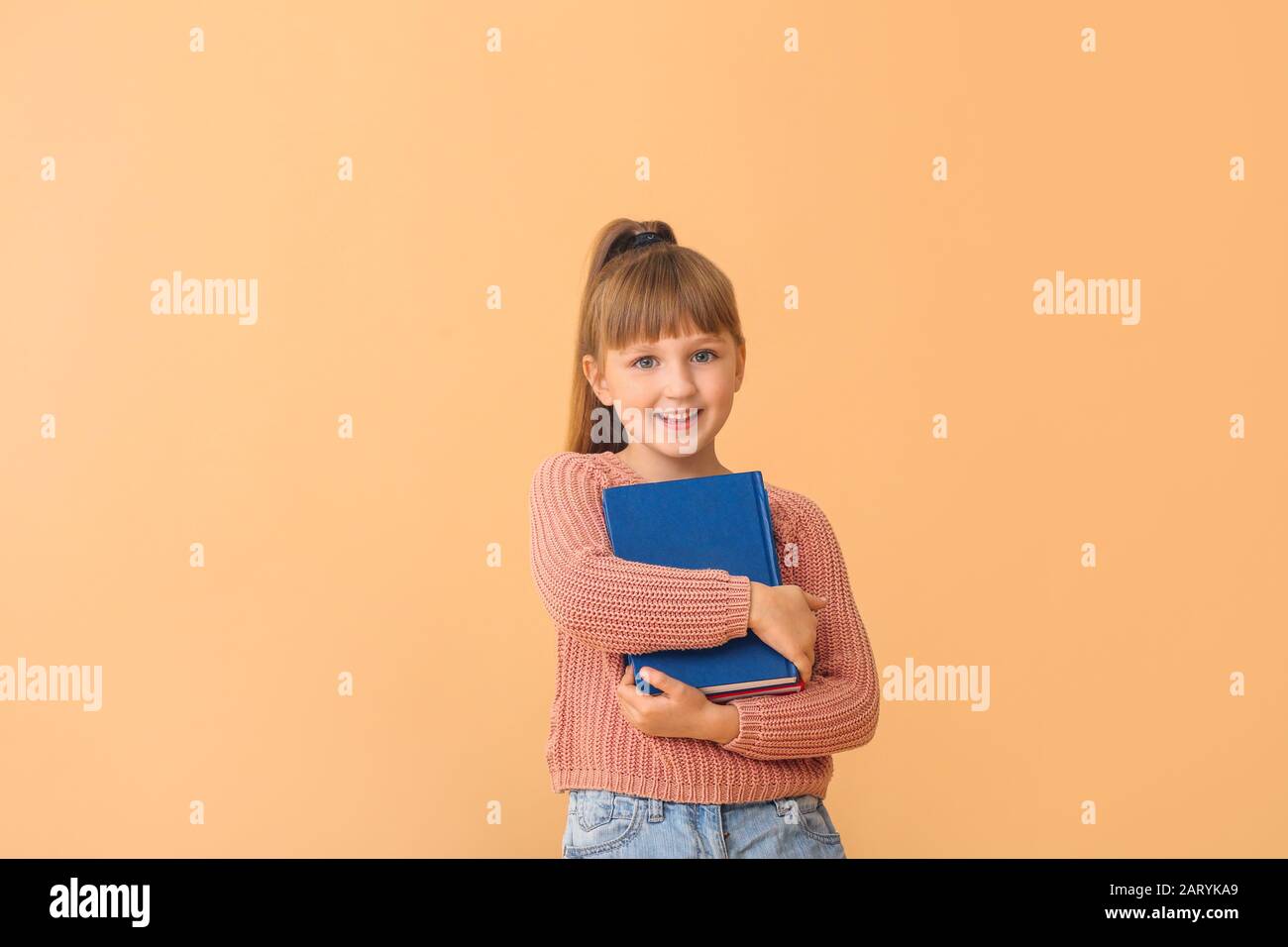 Cute little girl with books on color background Stock Photo - Alamy