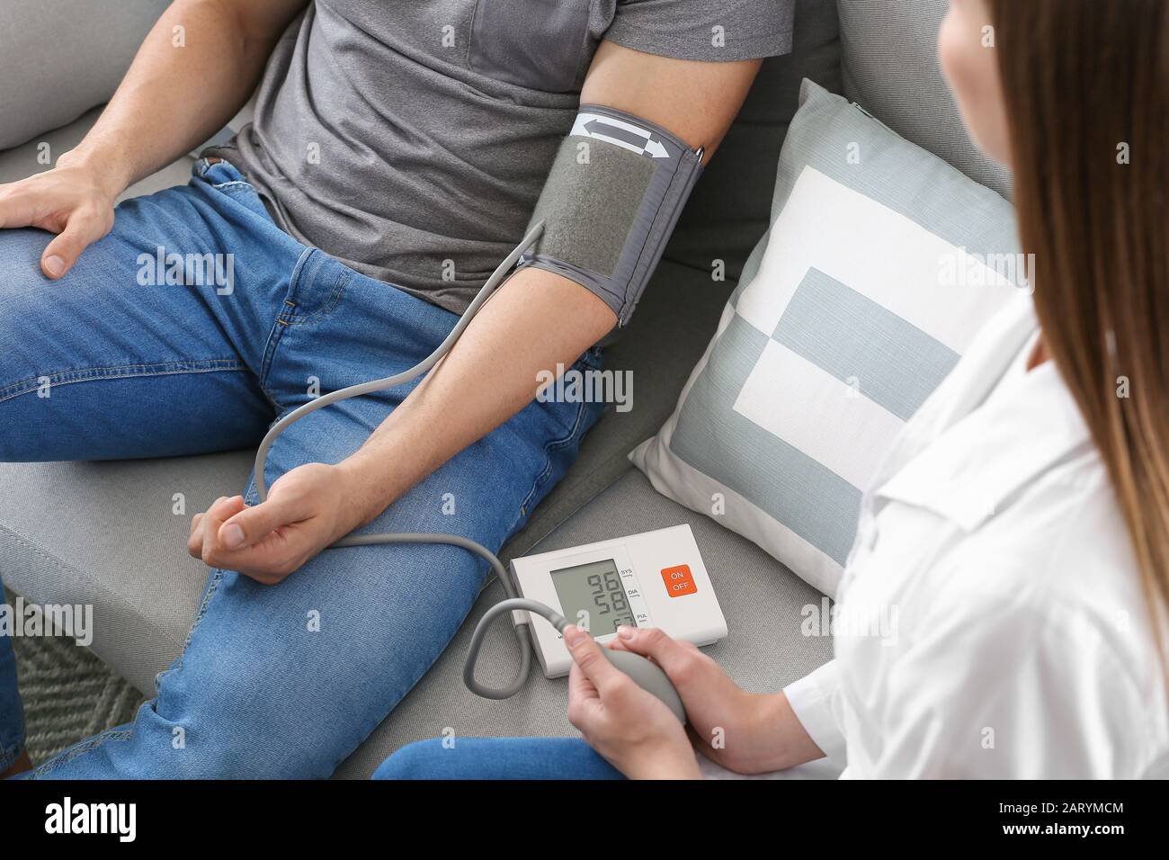 Doctor measuring blood pressure of young man at home Stock Photo - Alamy