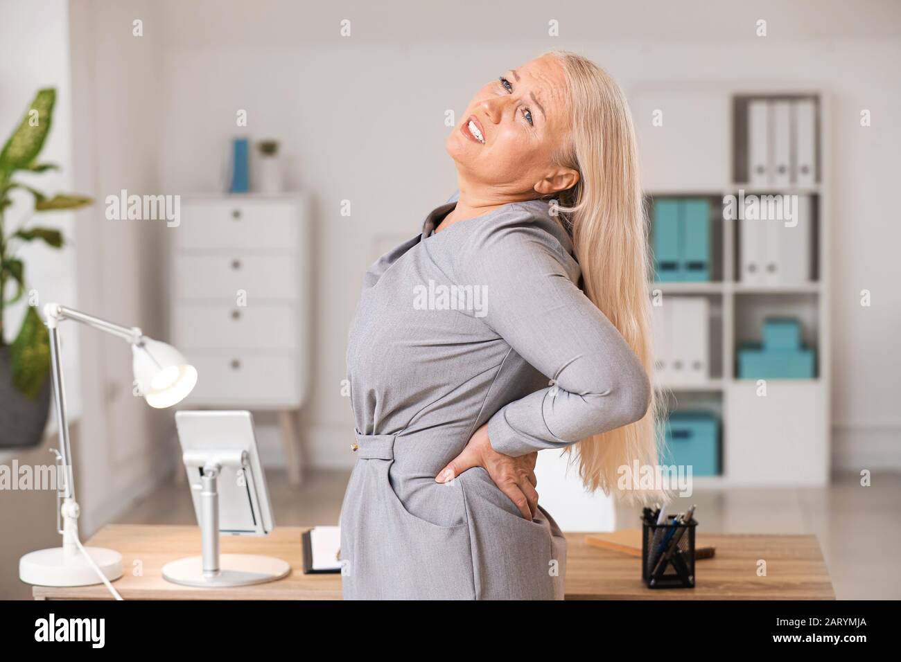 Mature woman suffering from back pain in office Stock Photo Alamy