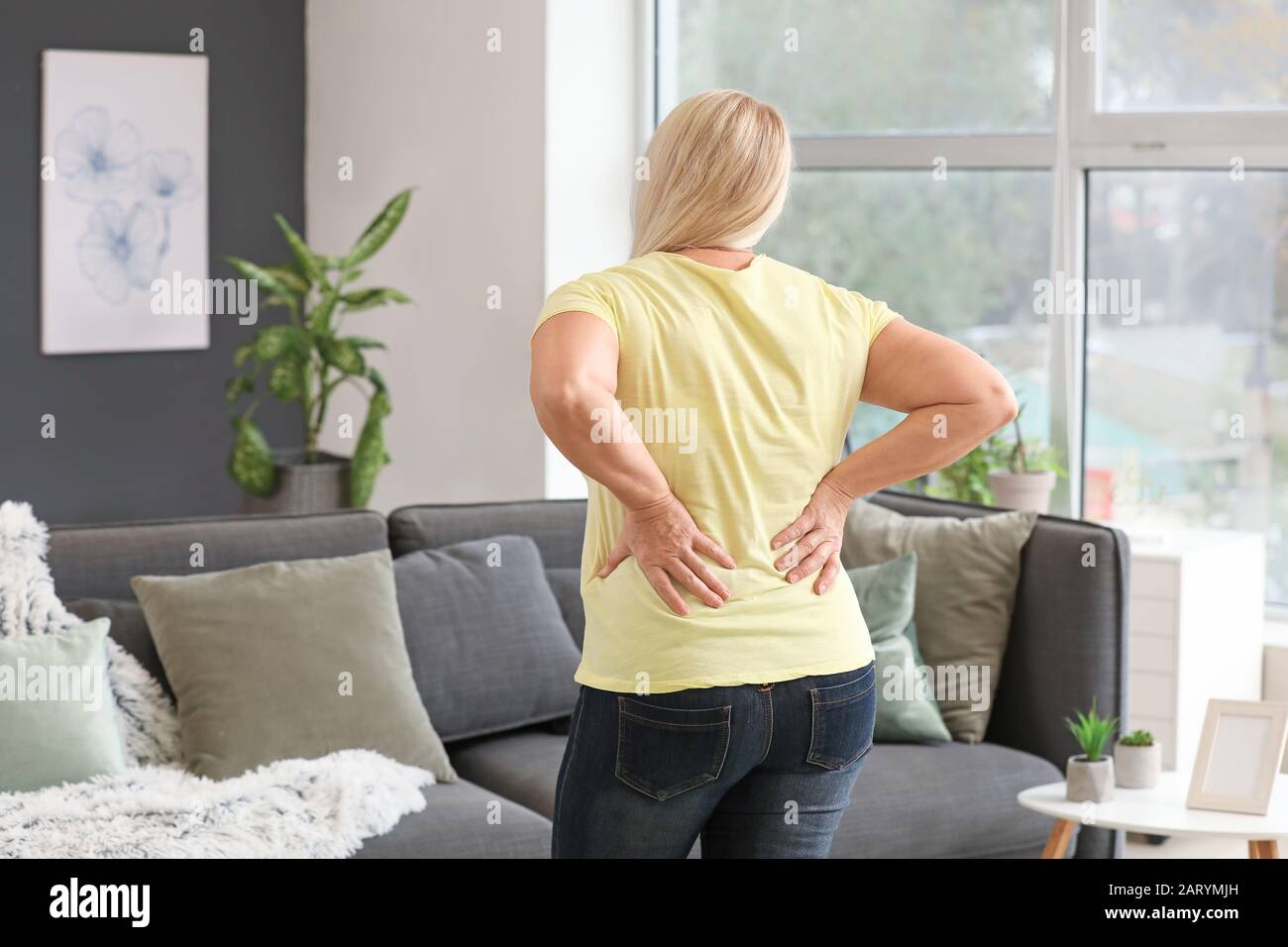 Mature woman suffering from back pain at home Stock Photo - Alamy