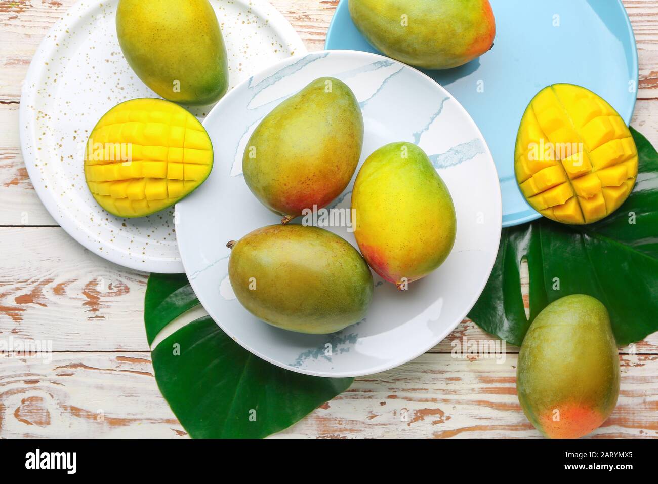 Plates with sweet ripe mangoes on wooden table Stock Photo
