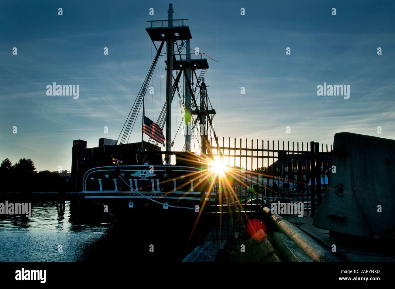 USS battle ship is settled on the harbor with star-like sun Stock Photo