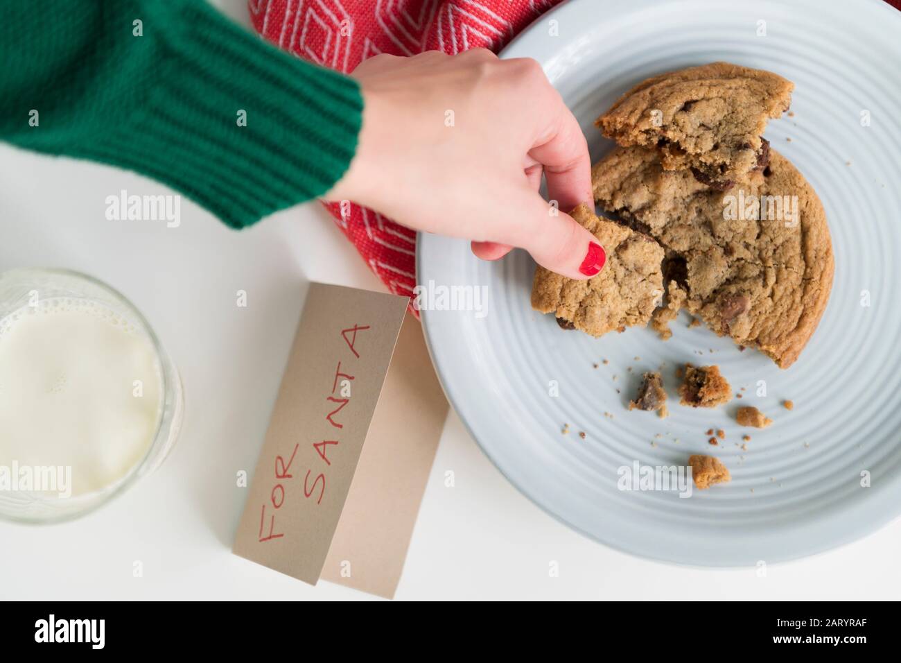 Woman picking up cookie by card for Santa Stock Photo