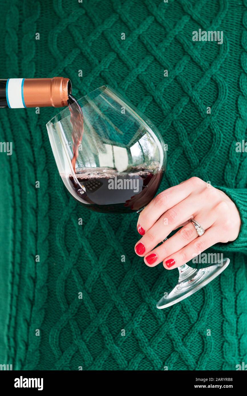 Woman wearing green pouring glass of wine Stock Photo