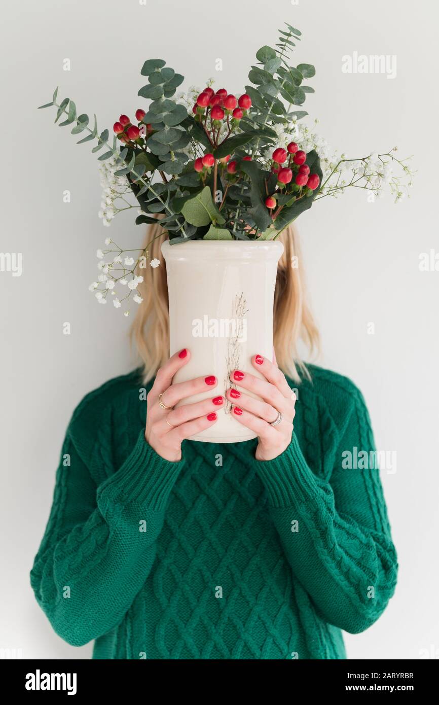 Woman wearing green holding vase of flowers Stock Photo