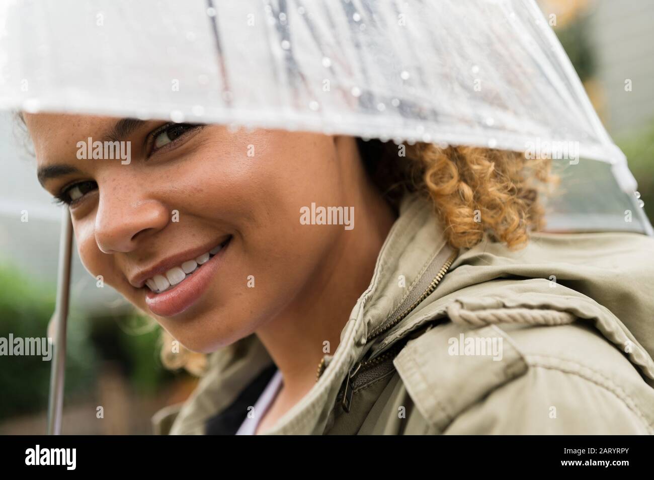 Smiling woman under wet umbrella Stock Photo