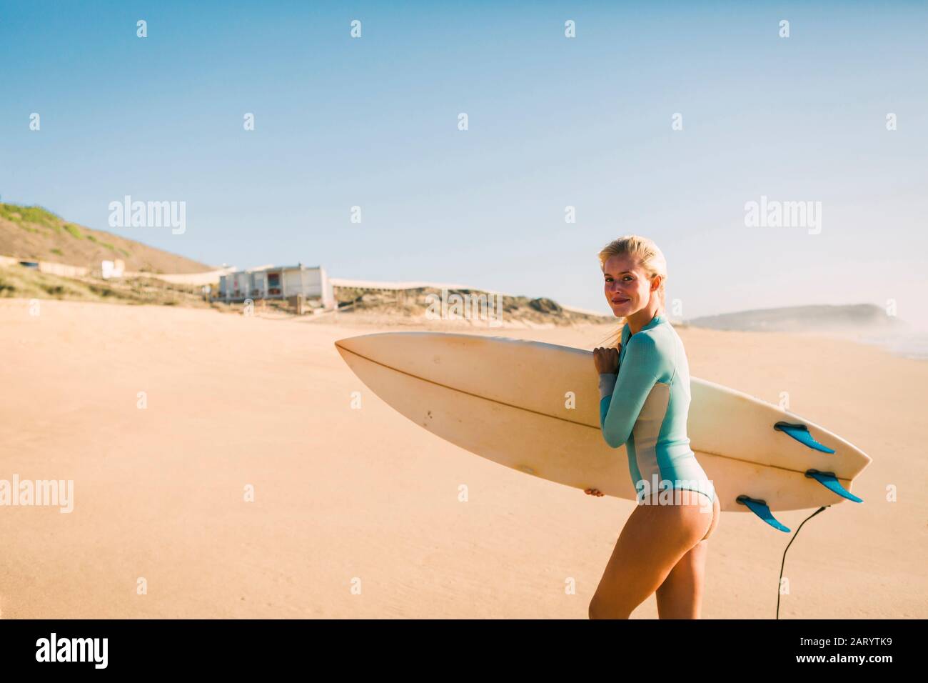 Woman wearing wetsuit holding surfboard on beach Stock Photo - Alamy