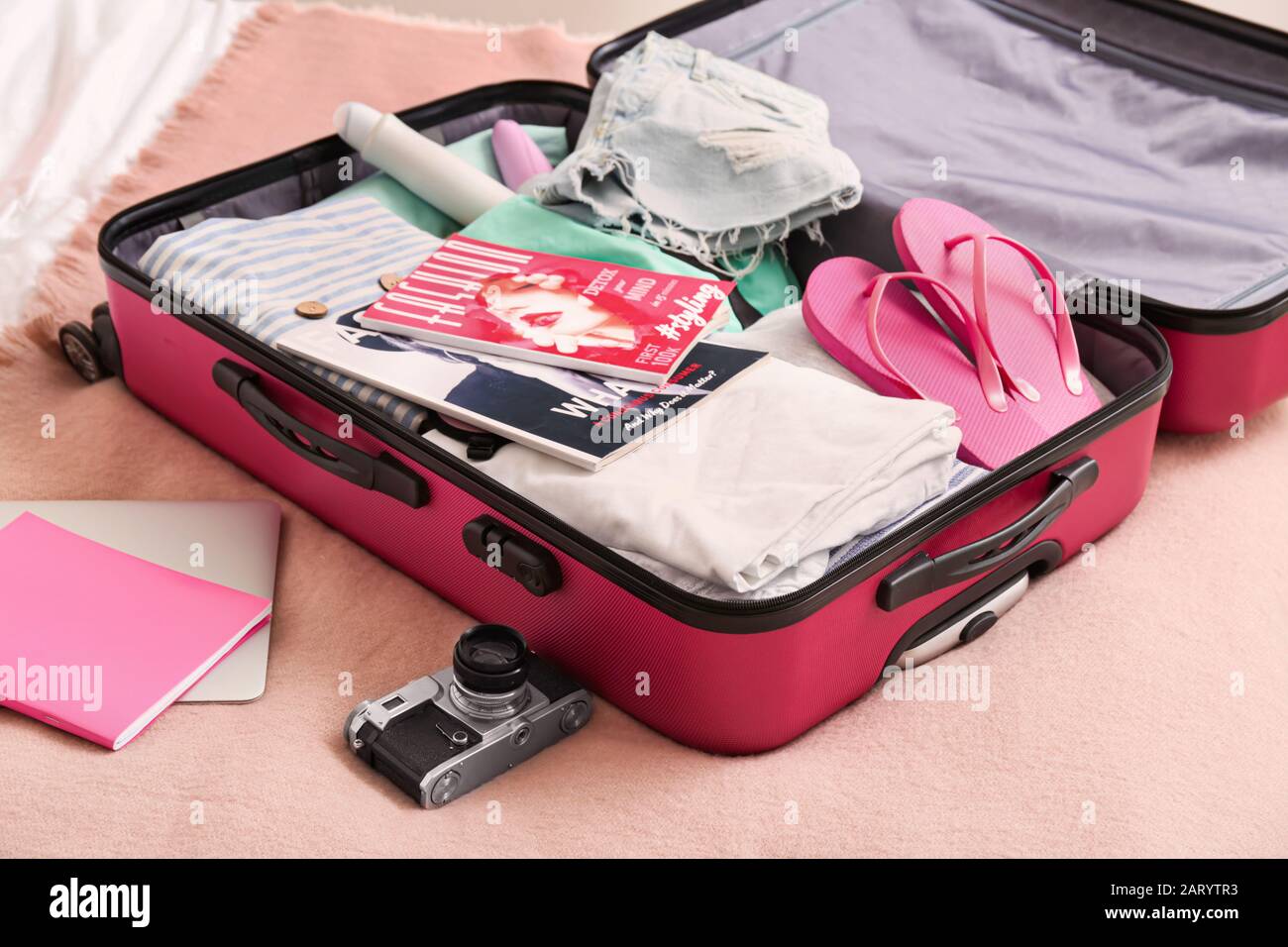 Open suitcase with packed clothes and accessories on bed Stock Photo