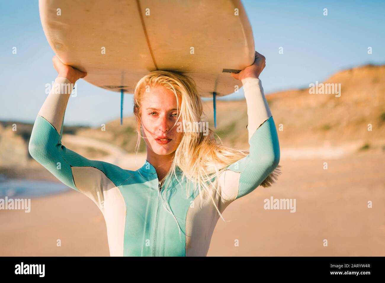 Woman holding surfboard above her head at beach Stock Photo - Alamy