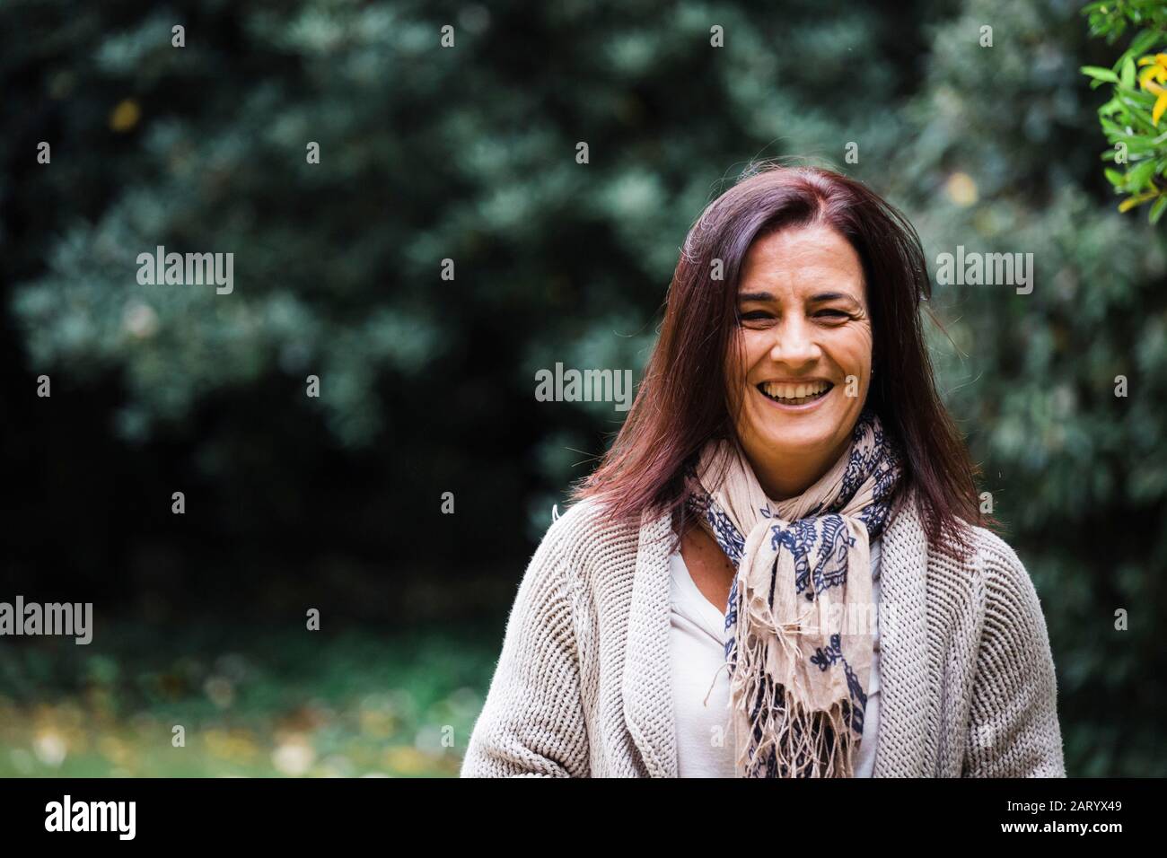 Smiling woman by trees Stock Photo