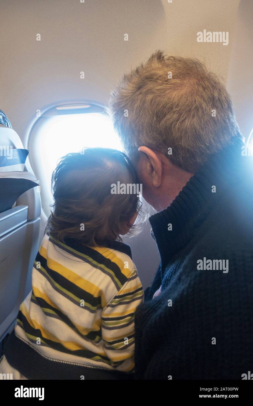 Man and child looking out airplane window Stock Photo