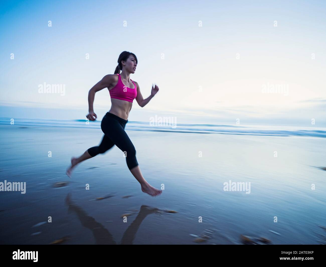 Young woman running on beach Stock Photo