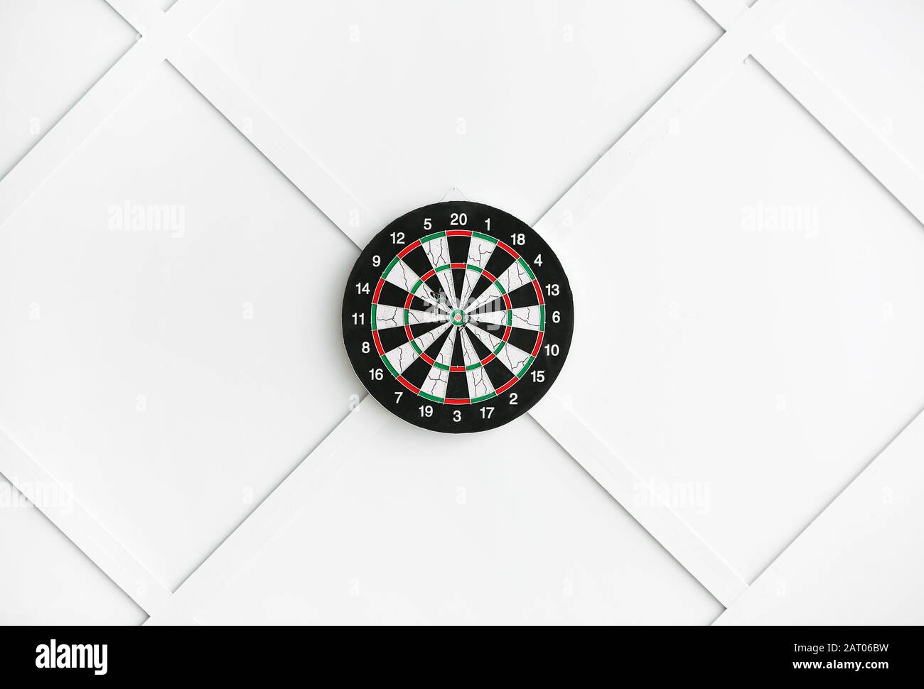 Dartboard hanging on light wall Stock Photo